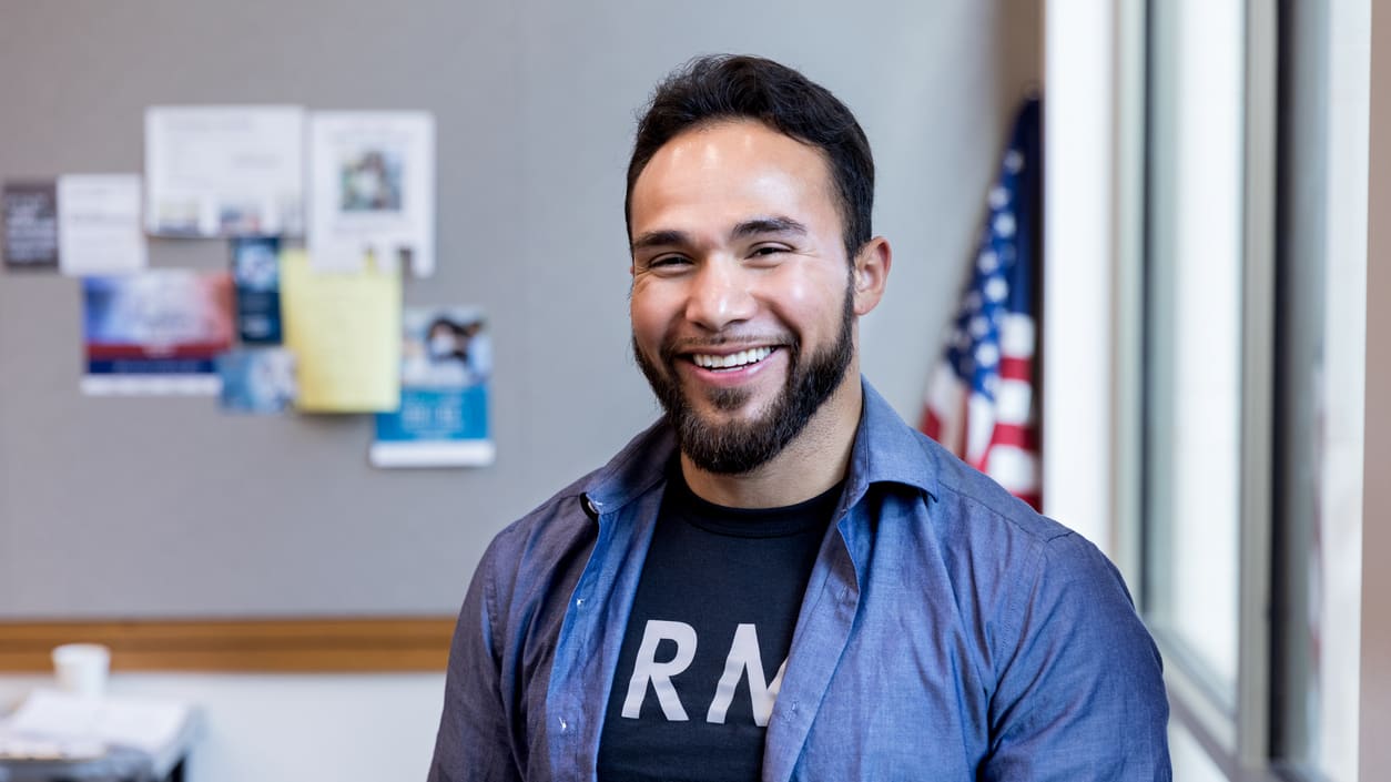 A man with a beard smiling in an office.