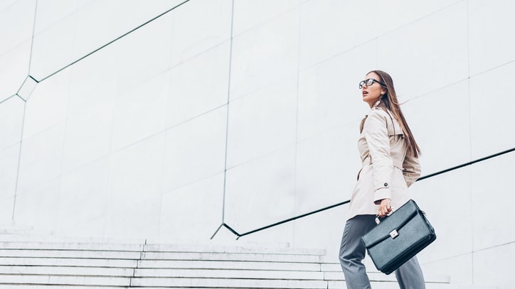 A business woman is walking down stairs with a briefcase.