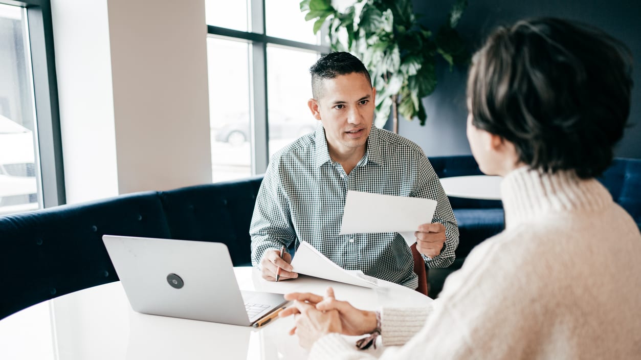 A man and woman sitting at a table in an office.