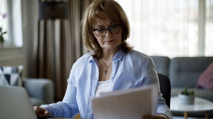 A woman sitting at a table with a laptop and papers.