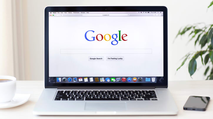 A laptop with the google logo on it sitting on a table.