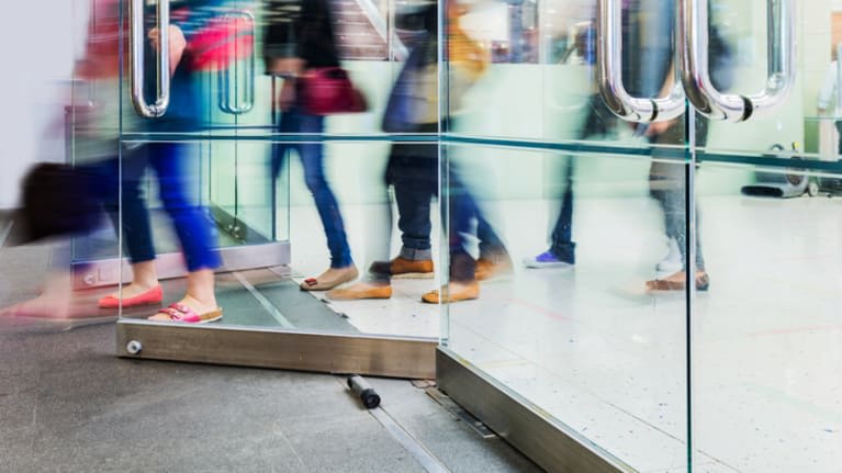 A group of people walking through a glass door.