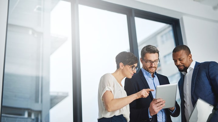 Four business people looking at a tablet in an office.