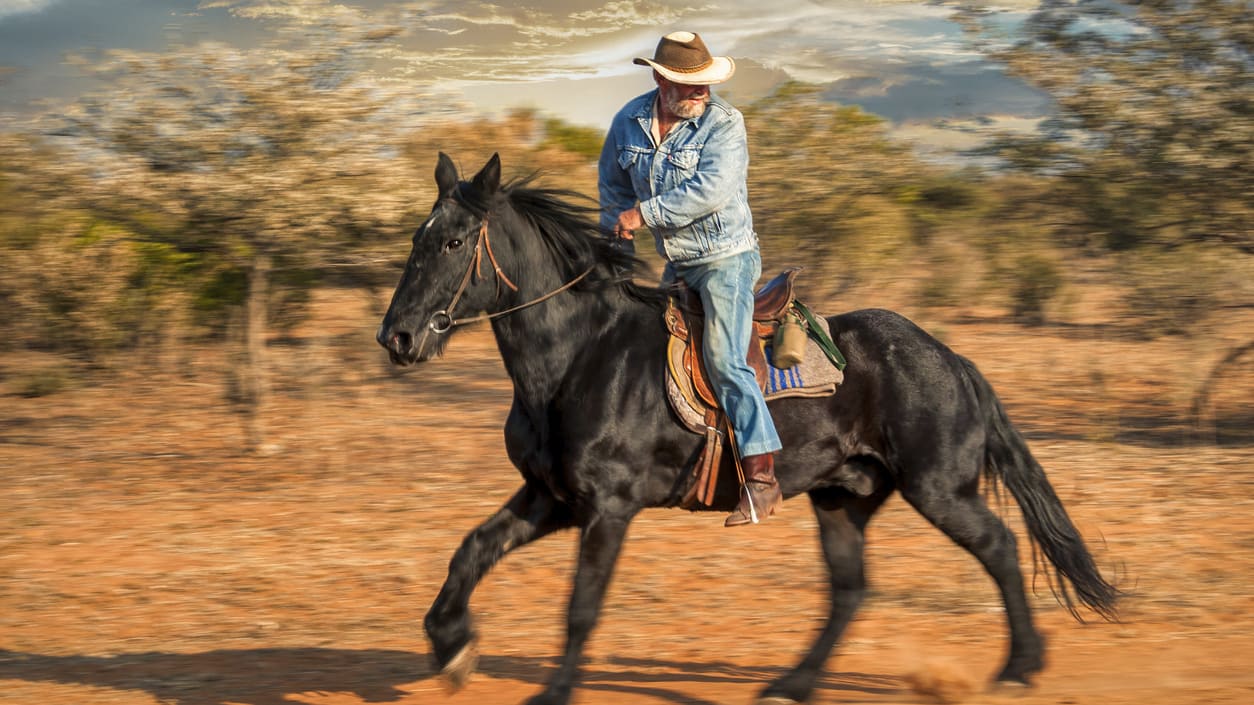 A man riding a black horse on a dirt road.