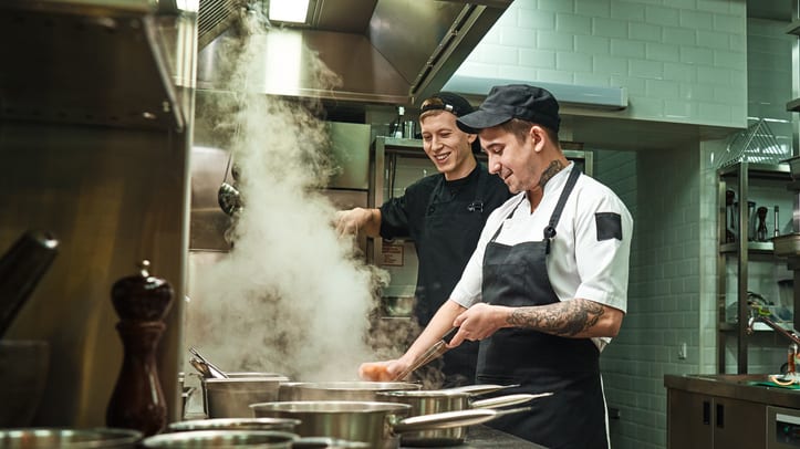Two chefs preparing food in a commercial kitchen.