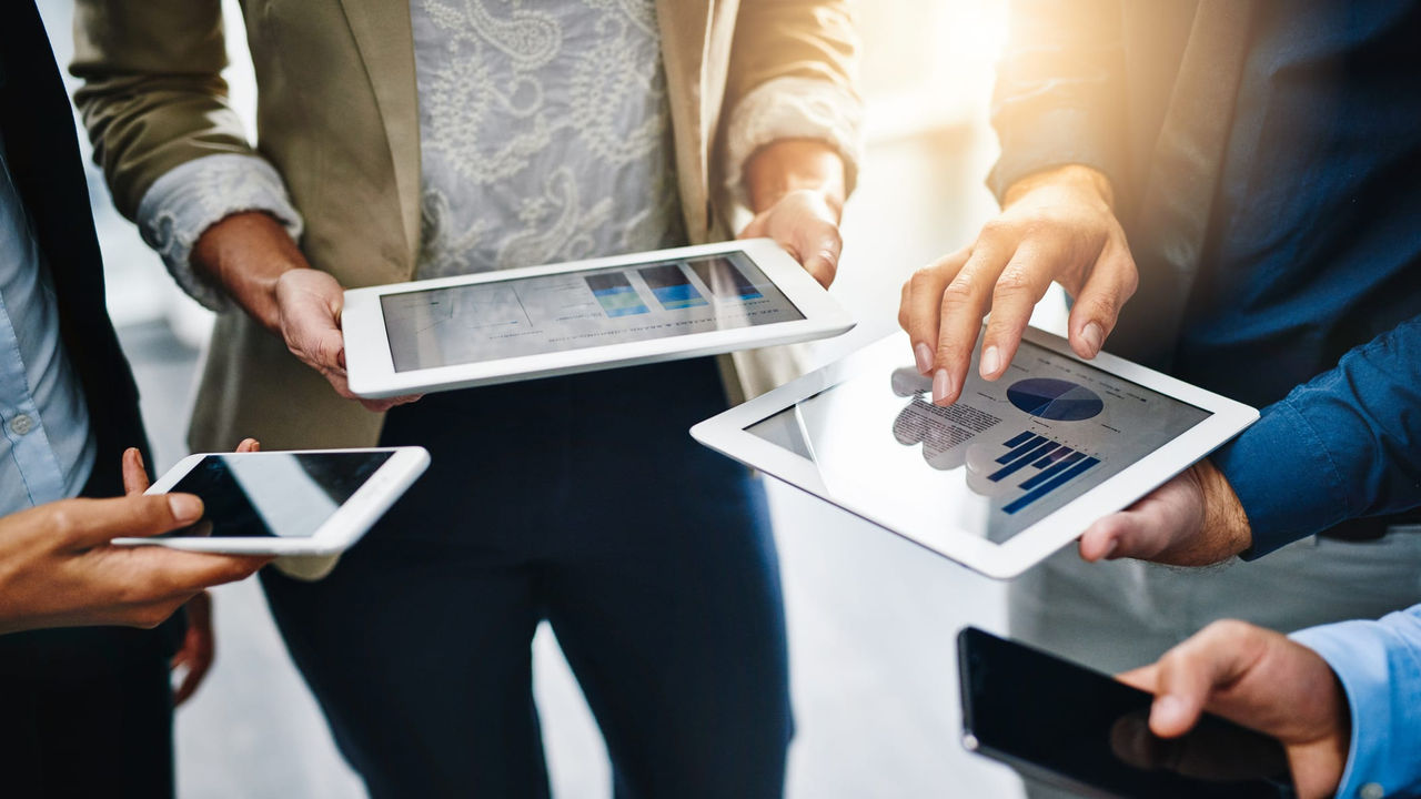 A group of business people holding a tablet with graphs on it.